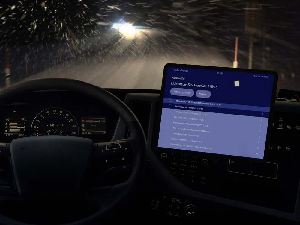 Tablet mit der nosnow-App im Cockpit eines Räumfahrzeugs bei Schneefall